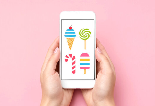 Hands holding smartphone with colorful ice cream candy and lollipop icons on screen flat design