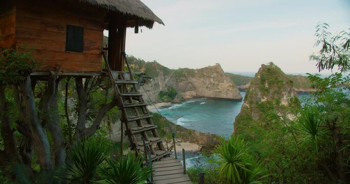 Wooden treehouse overlooks turquoise ocean bay and sheer cliffs at Diamond Beach Nusa Penida