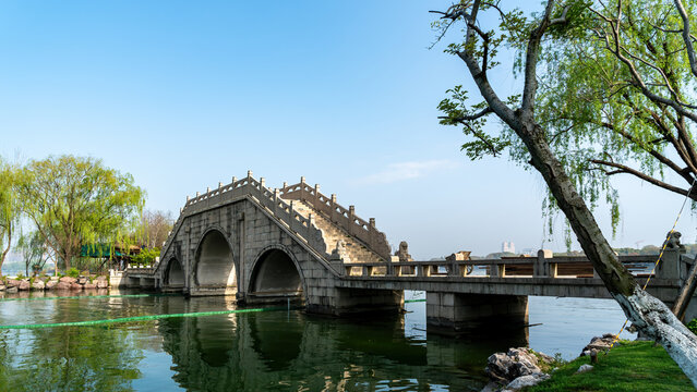 Ancient Stone Arch Bridge Over Calm Lake Under Clear Blue Sky