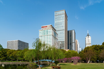 Naklejka premium Urban park with lake and modern buildings on clear sunny day