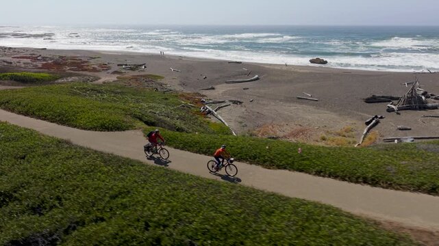 A mature man and woman enjoy biking on the Coastal Trail in Fort Bragg California while taking in views of the Pacific ocean.