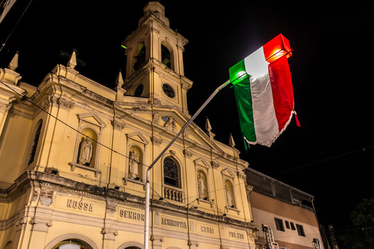 Low-angle night view of the historical facade of the Our Lady Achiropita Churchdecorated with Italian flags and illuminated street lamps 