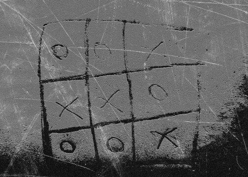 Tic tac toe game drawn on a dusty textured surface with scribbled X's and O's for a vintage feel.