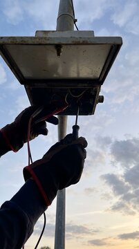 Electrician testing wires in a street light junction box outdoors