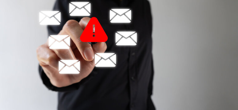 Hand interacting with a red warning symbol among floating email icons