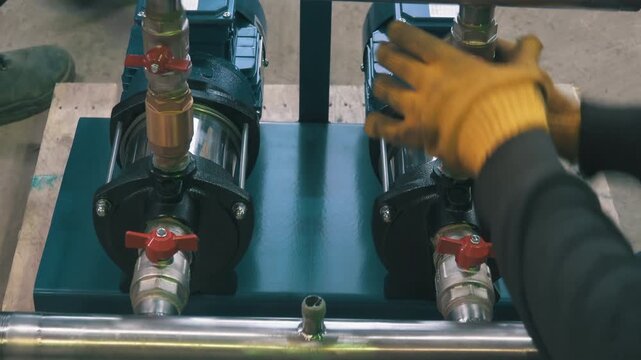 Two Workers Mounting Water Pumps on Steel Frame | Technicians Assembling Twin Pump System with Ball Valves | Top-Down View of Industrial Pump Installation