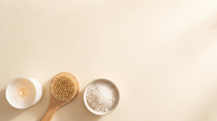 Plakat Top view of a wooden dry brush with sea salt in a ceramic bowl and a lit candle on a beige background for a minimalist spa wellness concept with ample copy space for branding