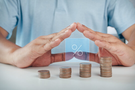 Hands protecting growing coin stacks with digital percentage interest rate hologram icon, concept of financial investment growth, high return on investment, savings, and banking interest.