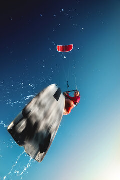 Low angle view of woman kiteboarding against blue sky