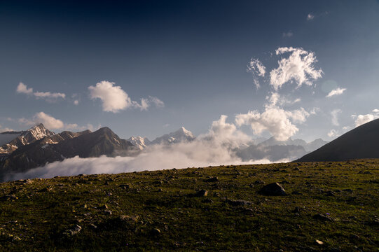 Mountain range with snow capped peaks above low clouds