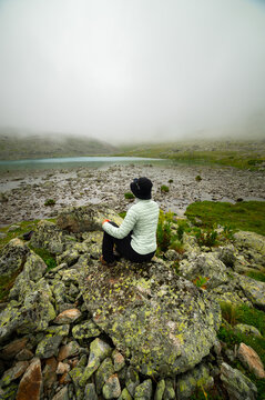 Female Person Sitting on Rock Facing Misty Mountain Lake