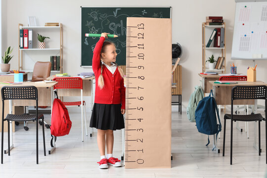 Child development and growth tracking, schoolgirl measuring height with a giant ruler in a classroom for educational progress and health monitoring