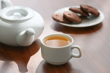 Fototapeta premium Relaxation and wellness break, tea cup with teapot and chocolate cookies on a wooden table for a cozy afternoon pause and mindfulness lifestyle