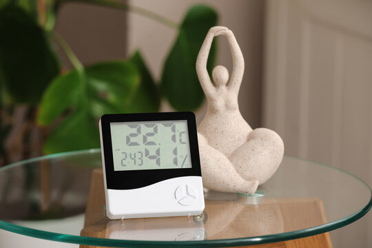 Indoor air quality and home wellness, digital hygrometer and thermometer monitoring humidity and temperature levels in a living room with yoga decor
