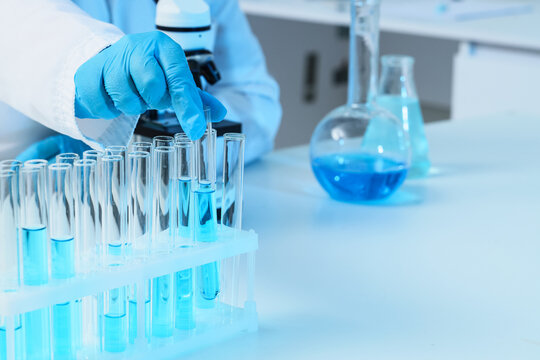 Medical research and pharmaceutical development, scientist hand in blue gloves testing chemical samples in laboratory test tubes for vaccine innovation