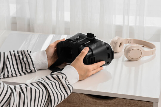 Virtual reality and digital immersion, person holding vr headset with headphones on desk for metaverse gaming and interactive technology experience
