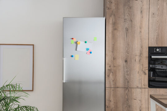 Household organization and family planning, blank notepad with colorful sticky notes on a modern stainless steel refrigerator in a contemporary kitchen