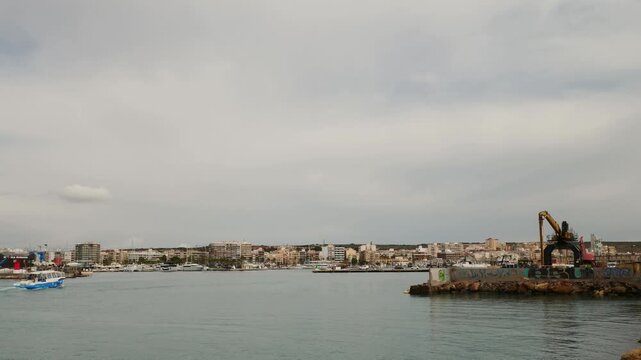 Ferry water taxi boat arriving at Santa Pola harbor from Tabarca Island under a dramatic overcast cloudy sky in Alicante Spain.
