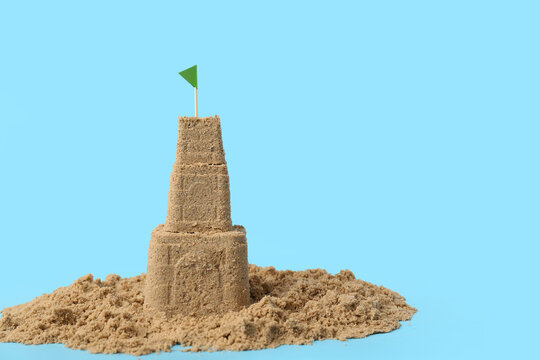 Beautiful sand castle with flag on blue background