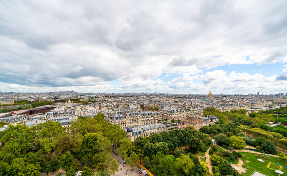 Panoramic aerial view of paris cityscape with green park under cloudy sky in france