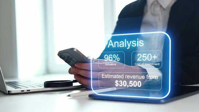 A person holds a smartphone while reviewing analysis data on a screen. The data includes actuators, investment costs, and revenue estimates. This scene takes place in a modern office.