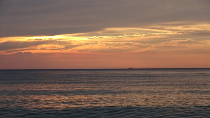 Fototapeta premium Vibrant Sunrise Over the Ocean Horizon with Dramatic Clouds. A breathtaking view of the sunrise over the peaceful ocean horizon, featuring dramatic golden and orange clouds in the sky.