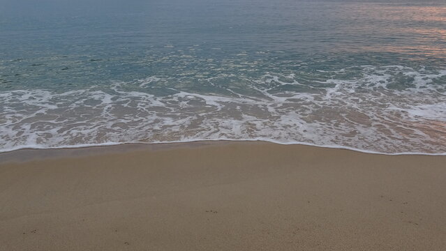 Calm Ocean Waves Reaching the Sandy Shore.
A tranquil view of calm sea waves rolling gently onto the soft sand of the beach during early morning.