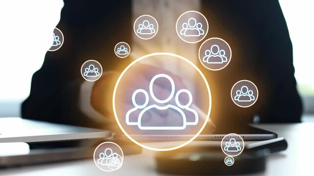 People are discussing digital tools for teamwork. They are using laptops and tablets during a business meeting at an office. Icons of users surround the group.