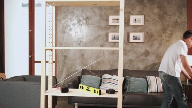 Asian mature man tests his self-assembling wooden furniture with DIY tools, endurance achievement satisfied, cheerful and proud home improvement accomplishment, hobby carpentry workshop handyman.