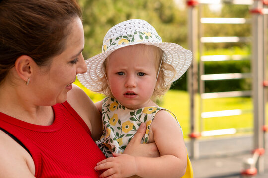 Mother Holds Toddler Daughter Wearing Sun Hat Outdoors