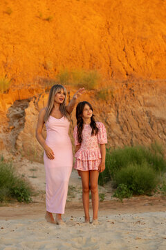 Mother Pointing Into Distance Beside Daughter Outdoors
