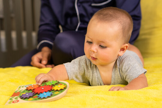 Baby Exploring Colorful Wooden Gear Toy On Blanket