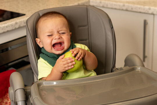 Crying Baby Boy Holds Green Apple At Mealtime
