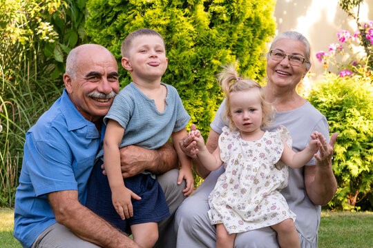 Grandparents Posing Playfully With Grandchildren in Summer Garden