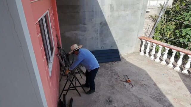 Young Worker Arranging Metal Stools on Rooftop Workspace