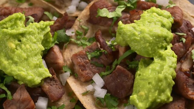 Close-up of carne asada tacos with fresh guacamole and chopped onion