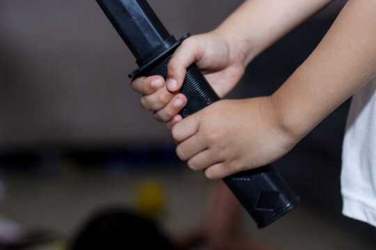 Close-up of hands firmly holding the black handle of a toy sword or katana.