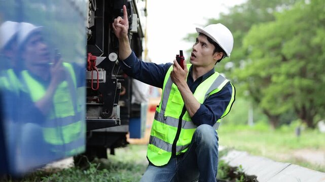 Railway engineer inspecting a train and talking on a walkie talkie