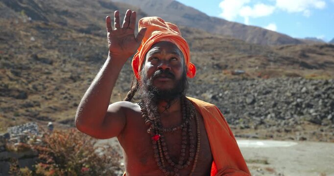 Annapurna Circuit, Mustang Nepal, Close-up shot of a Hindu holy man wearing an orange turban and rudraksha beads raising his hand in a hand gesture near the sacred Muktinath Temple