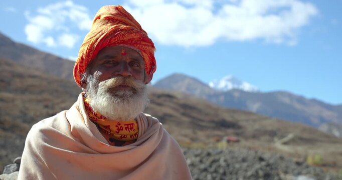 Annapurna Circuit, Mustang, Nepal close-up shot focusing on a Hindu holy man wearing traditional orange attire and a rudraksha mala near the sacred Muktinath Temple
