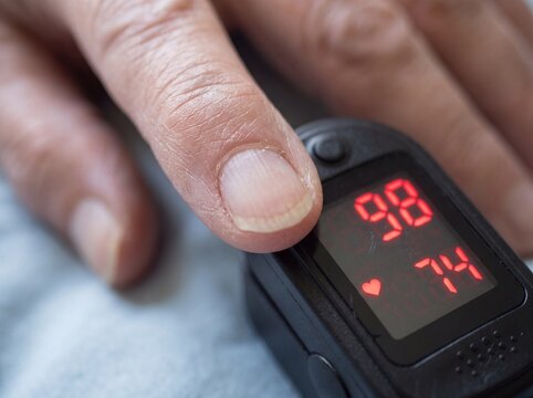 Close-up of a finger with a pulse oximeter attached showing readings.