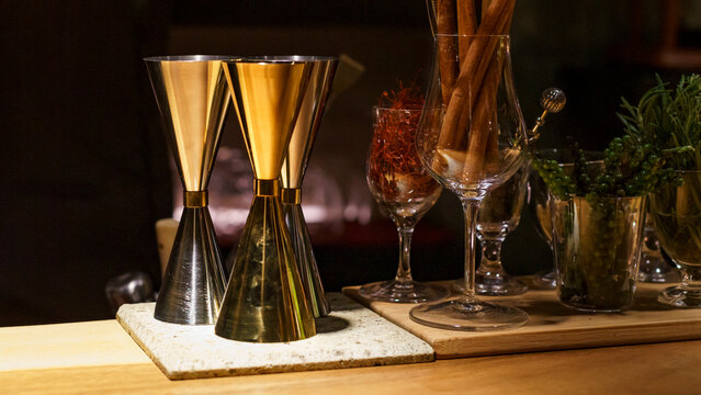 Equipment used for mixing cocktails, including mixing cups and various herbs, sits on a table inside a bar in Bangkok, Thailand, at night