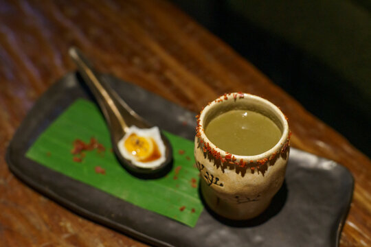 A glass of a unique cocktail "Kaprao Moo Krob Kai Dao Mai Sook (crispy pork with chili  basil and fried egg)" which is based on Thailand's food of the same name inside a bar in Bangkok, Thailand