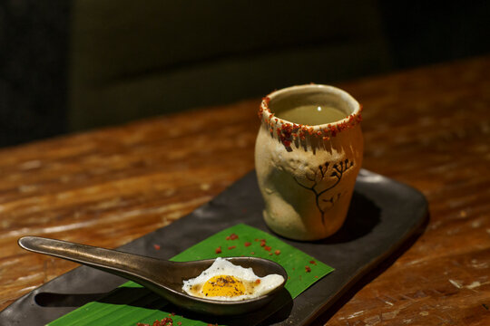 A glass of a unique cocktail "Kaprao Moo Krob Kai Dao Mai Sook (crispy pork with chili  basil and fried egg)" which is based on Thailand's food of the same name inside a bar in Bangkok, Thailand