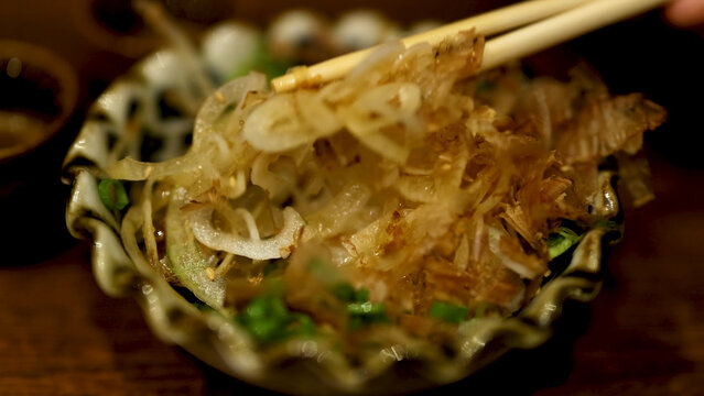 Chopsticks Picking Up Japanese Dish with Bonito Flakes and Onions