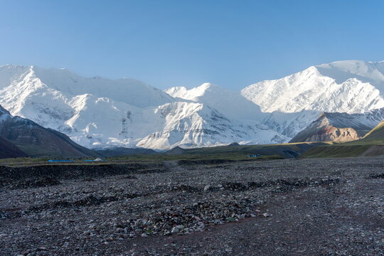 Snow-capped ridge of Lenin Peak from base camp with blue sky at sunrise in August