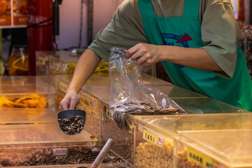 Obraz premium Vendor Bags Sunflower Seeds at Dihua Street Market