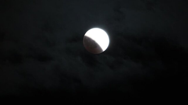 The moon during a partial lunar eclipse with clouds passing by.