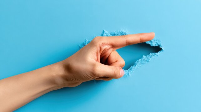 A finger pokes through a ripped hole in bright blue paper, concept for discovery.