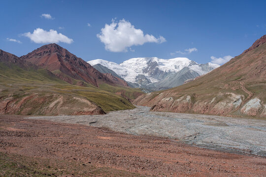 Colorful landscape view of red and grey river junction with snowcapped mountains in high altitude Trans Alay range, Bordobo, Osh, Kyrgyzstan